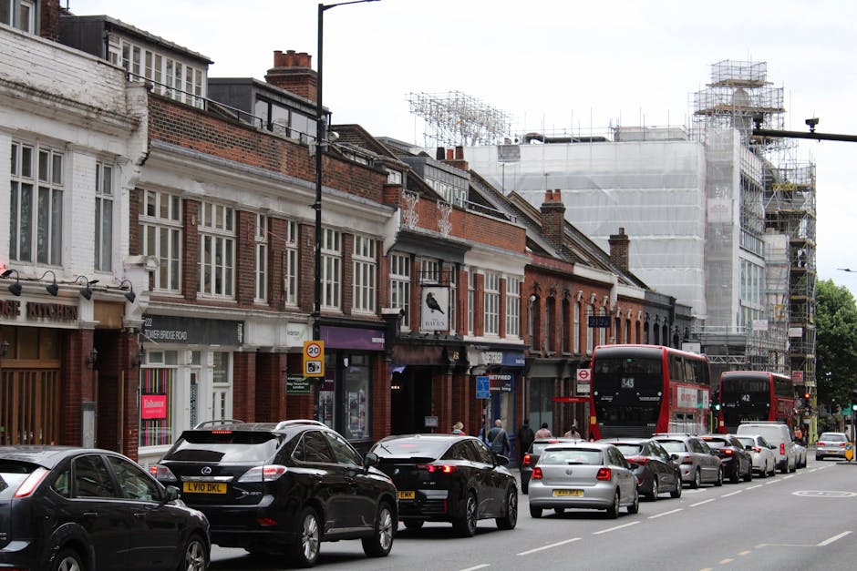 A row of traditional brick and white-painted terraced houses on Sidcup High Street, with multiple windows and storefronts at street level, some with signage visible. In front of the buildings, a busy 